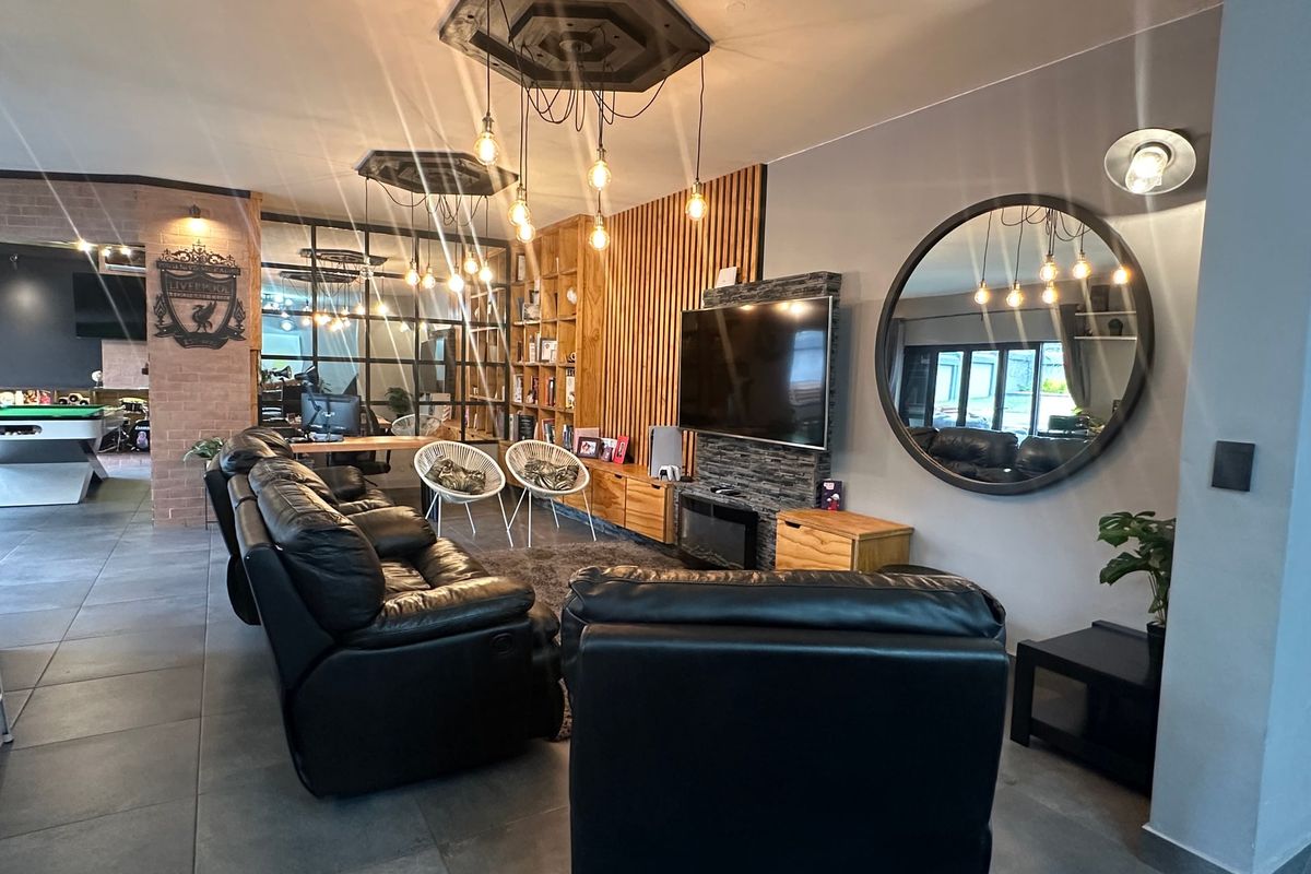 Modern living room featuring a stone fireplace, slatted timber wall accents, built-in shelving, and an industrial glass partition leading to an adjacent space.