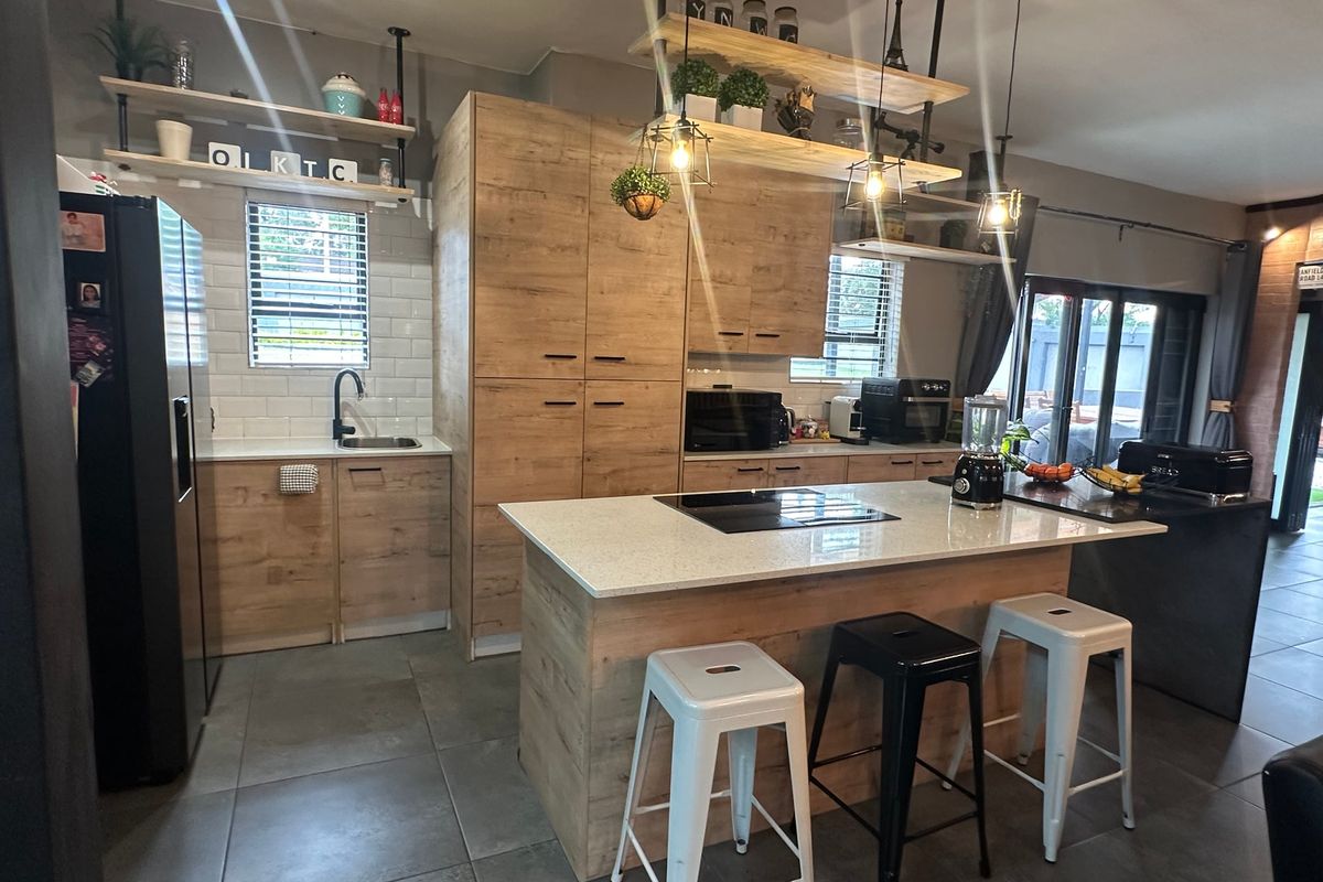Modern kitchen featuring wood-finish cabinetry, stone countertops, a central island with an induction cooktop, subway tile backsplash, and stylish open shelving.