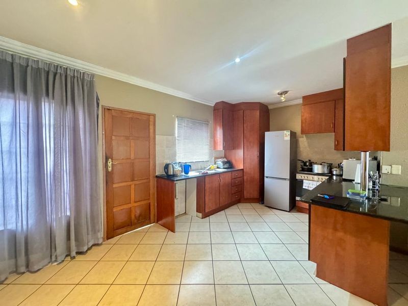 Functional kitchen featuring wooden cabinetry, granite countertops, tiled flooring, and integrated cooking appliances, offering a practical layout for daily meal preparation.
