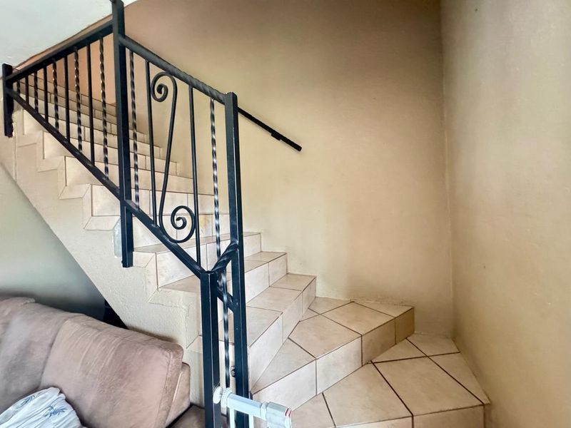 A staircase featuring tiled steps and a decorative wrought iron balustrade, providing access between levels within the townhouse.