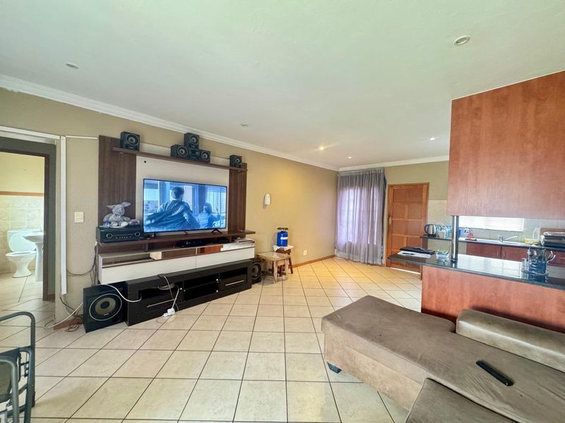 Open plan living area featuring tiled flooring, recessed lighting, and a kitchen breakfast bar, creating a functional and connected space for daily living.