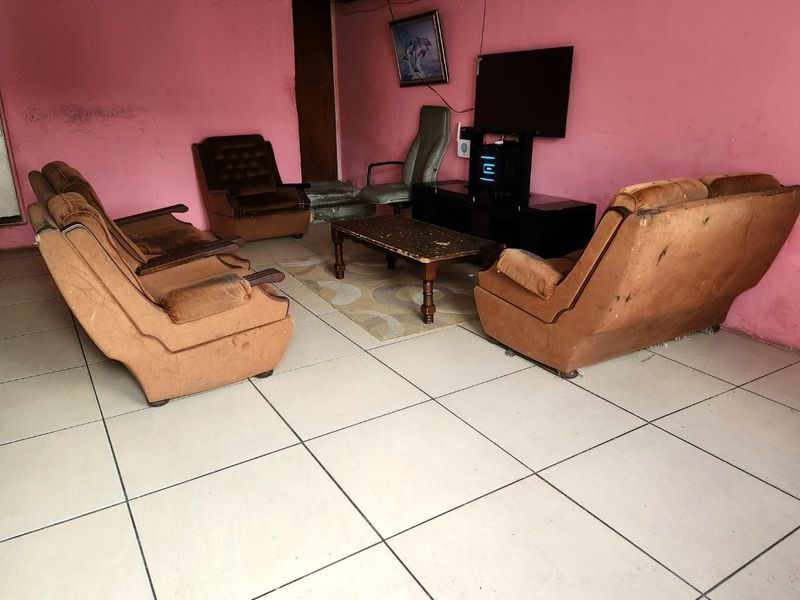 A living room space featuring tiled flooring and pink painted walls in need of cosmetic refurbishment.