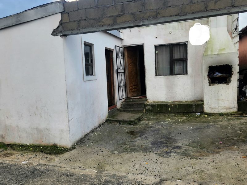 Front exterior view of a house featuring a concrete driveway, built-in braai, and security gate entrance.