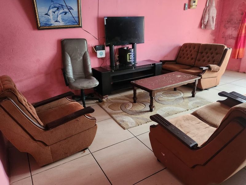A living room area featuring tiled flooring and pink painted walls that require maintenance and cosmetic updates.