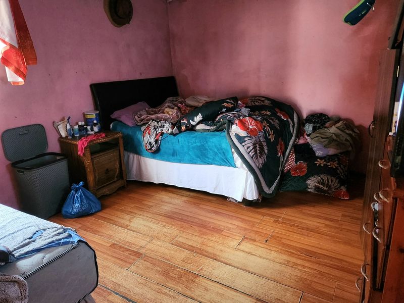 A bedroom featuring wood-look tile flooring and pink painted walls in need of cosmetic refurbishment.