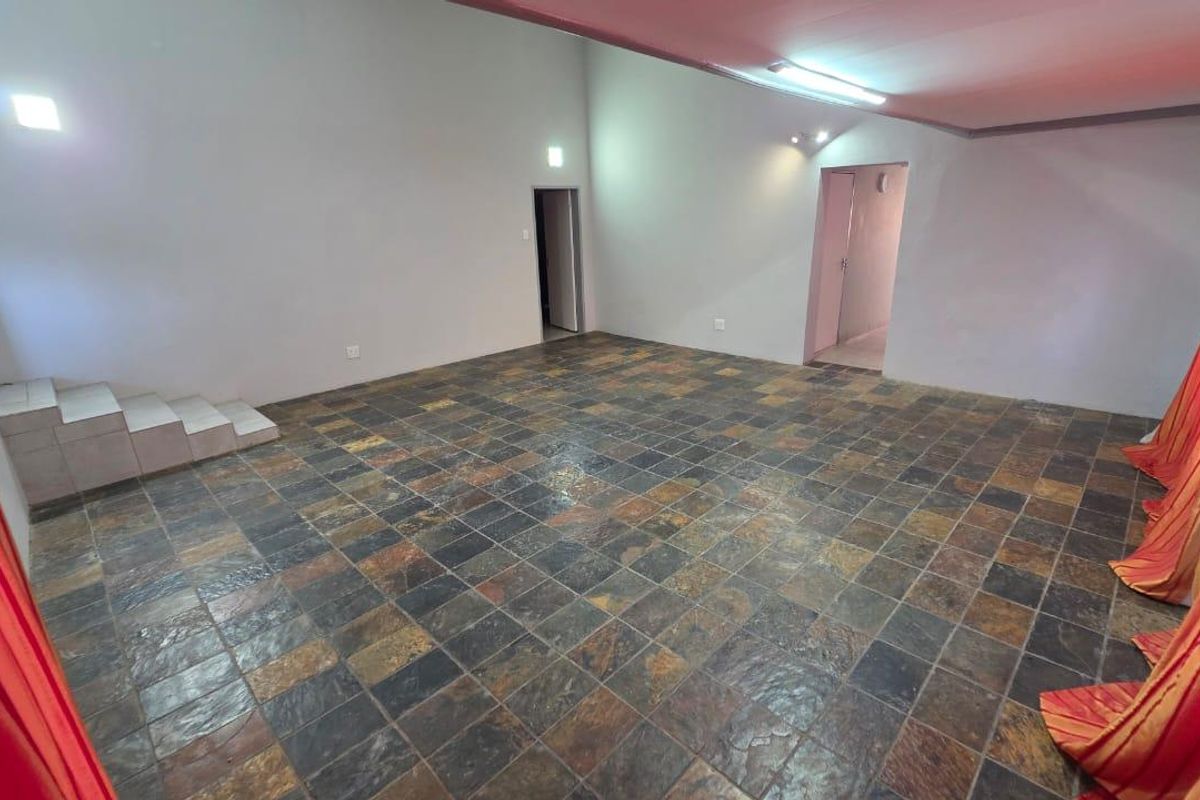 A spacious, empty living area featuring natural slate tile flooring and a raised platform, offering a blank canvas for interior design.