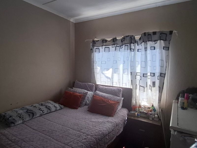 A standard bedroom featuring neutral wall tones and a window with fitted curtain tracks.