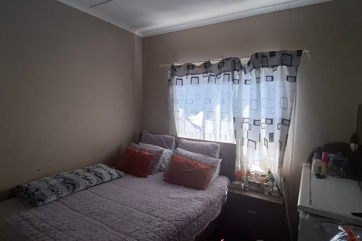 A standard bedroom featuring neutral wall tones and a window with fitted curtain tracks.
