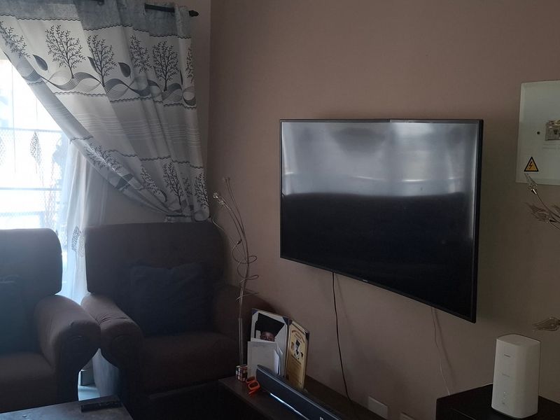 A living room area featuring a wall-mounted television and an exposed electrical distribution board.