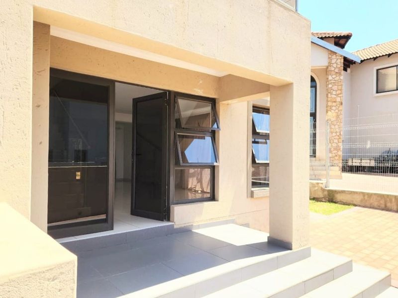 A covered patio area featuring tiled flooring, aluminium window frames, and security screen doors, providing a clean transition to the interior living space.