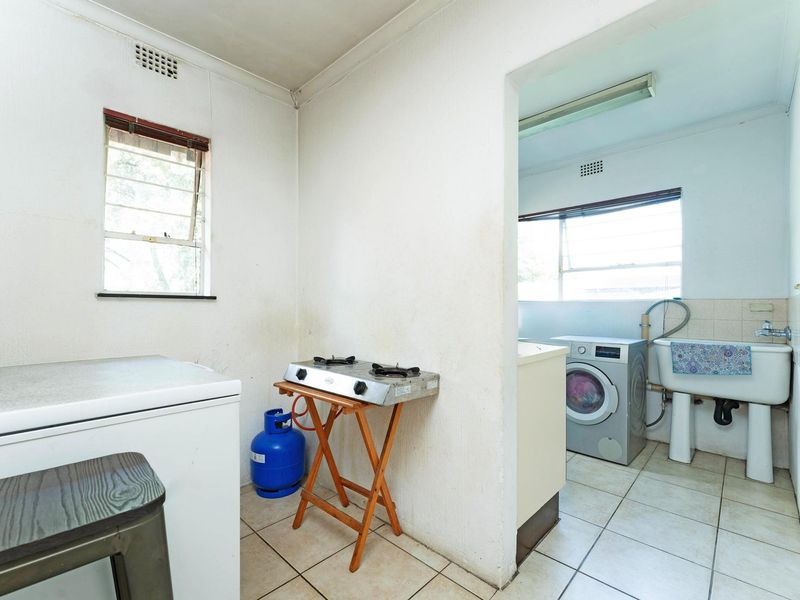 A functional laundry area featuring tiled flooring, a utility sink, and plumbing connections, providing a practical space for household washing tasks.