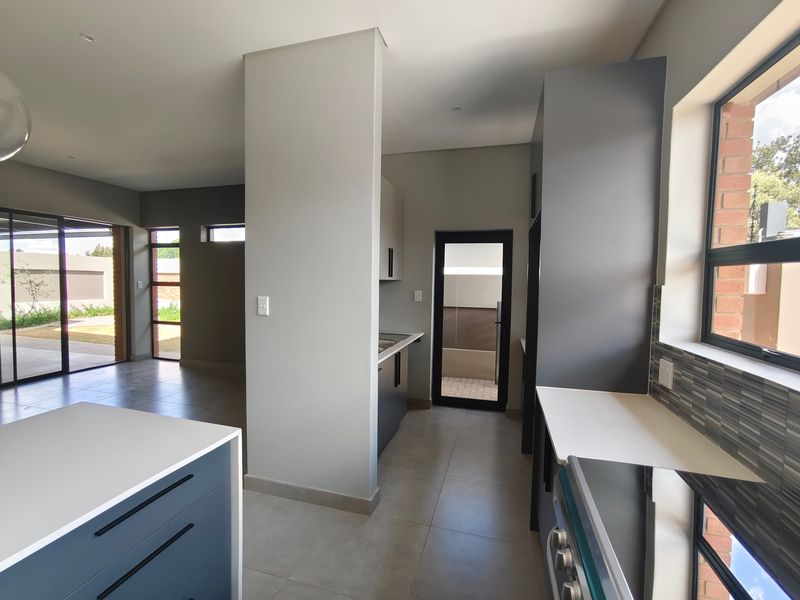 Modern open-plan kitchen and living area featuring sleek cabinetry, tiled floors, and large sliding doors leading to an outdoor patio space.