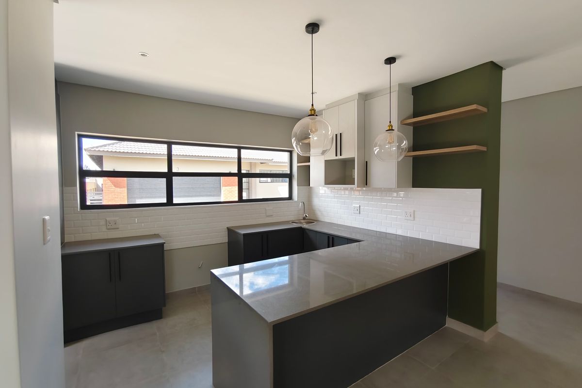 Modern kitchen featuring dark cabinetry, quartz countertops, subway tile backsplash, and floating shelves in a clean, contemporary open-plan layout.