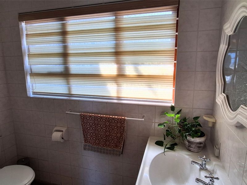 A functional bathroom featuring ceramic wall tiling, a pedestal basin with dual-handle mixer, and a standard toilet.