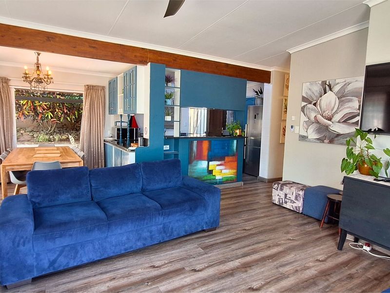 Spacious open-plan living and dining area featuring laminate flooring, exposed timber beams, and a functional kitchen with a breakfast bar.