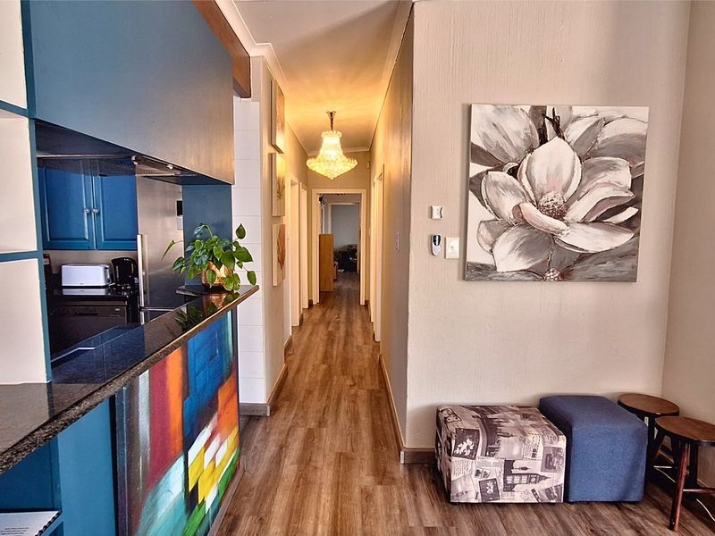 Open plan living area featuring laminate flooring, a kitchen with granite countertops, and a hallway leading to the rest of the home.