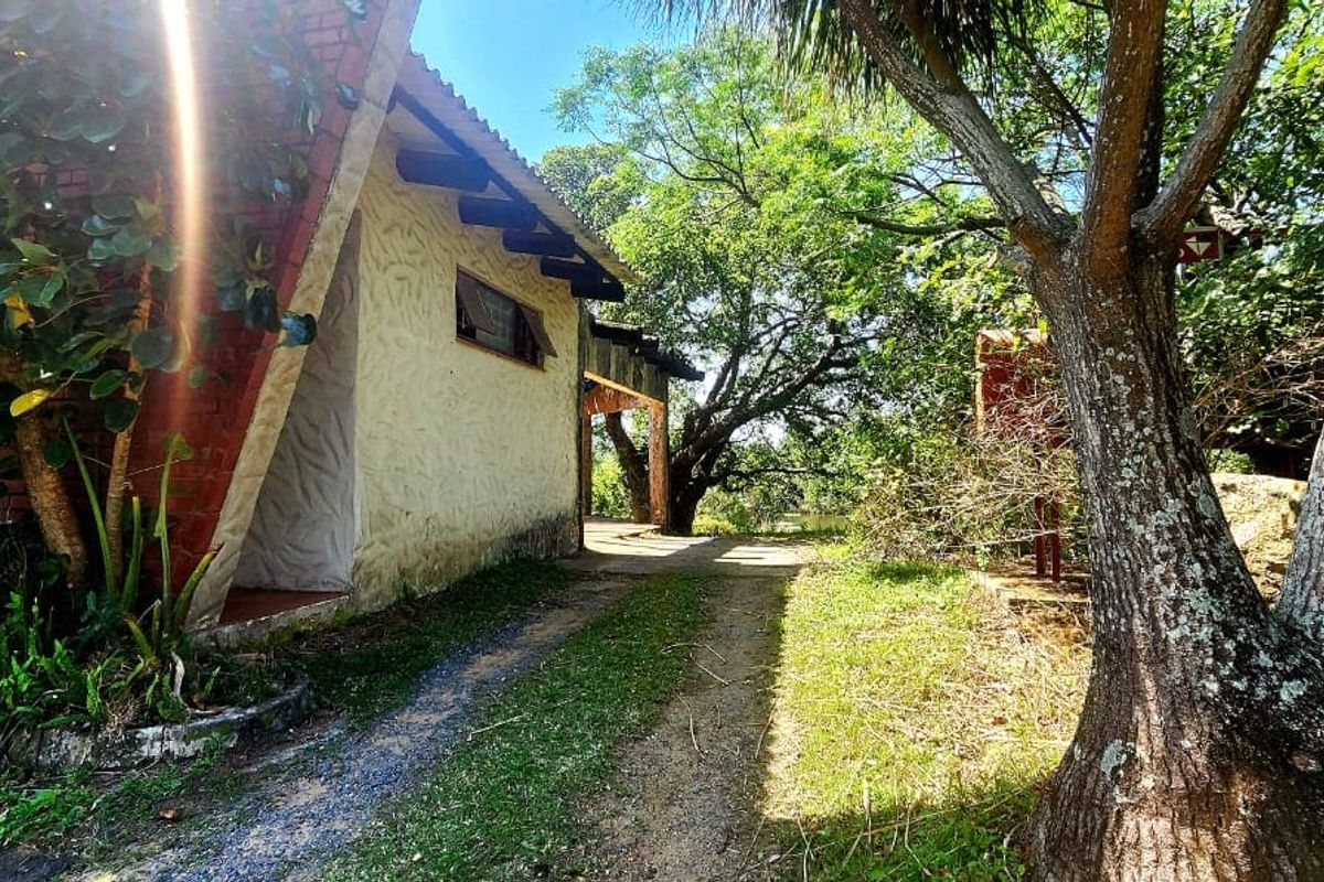 A view of the rear exterior of the farm property, featuring textured stucco walls, exposed brick accents, and timber rafters set within a natural landscape.