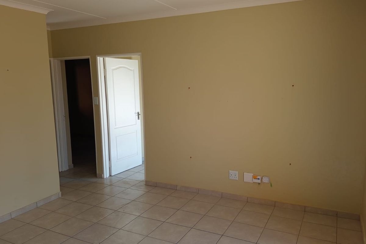 An empty living area featuring tiled flooring, coved ceilings, and neutral wall finishes, providing a blank canvas for personalization.