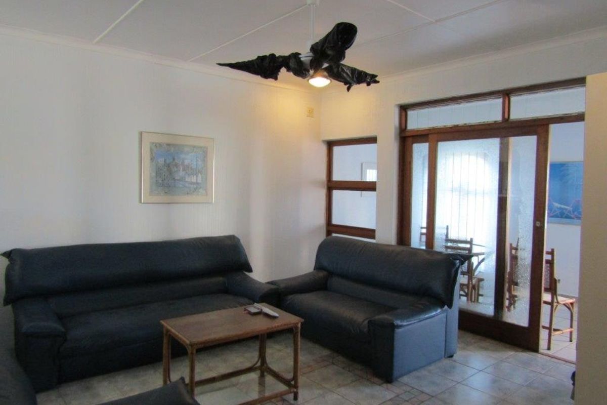A living room featuring tiled flooring, a ceiling fan, and sliding glass doors leading to an adjacent space.