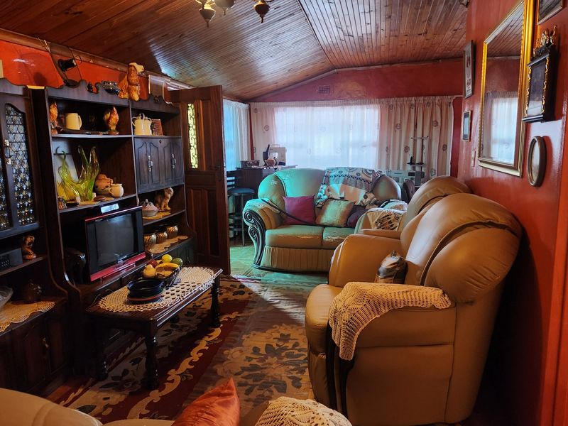 A living room featuring a vaulted timber-clad ceiling and built-in cabinetry, offering a traditional aesthetic with potential for modernization.