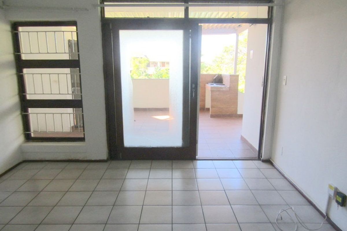 An empty living area featuring tiled flooring and a sliding glass door providing direct access to an outdoor patio space.
