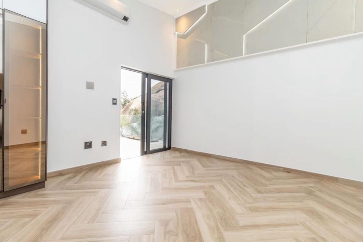 A bright, modern living space featuring herringbone timber flooring, built-in display cabinetry, and direct access to an outdoor area through a sliding glass door.