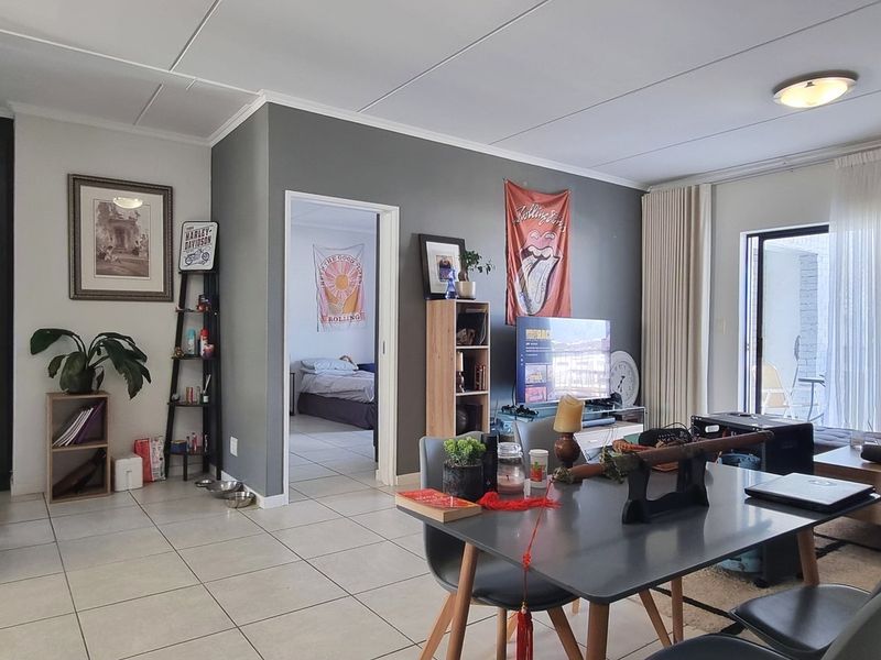 An open-plan living and kitchen area featuring tiled flooring, neutral wall tones, and direct access to an outdoor patio through a sliding glass door.