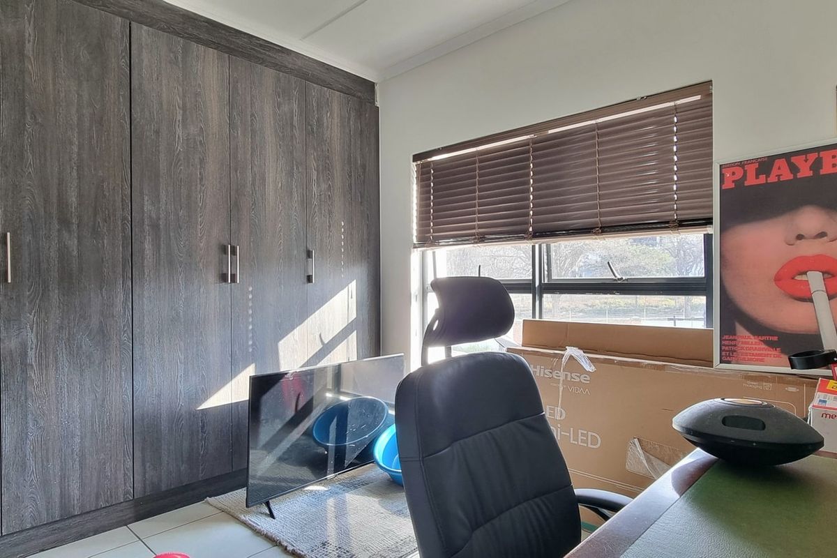 A bedroom featuring dark wood-grain built-in cupboards and venetian blinds, providing ample storage and natural light control.