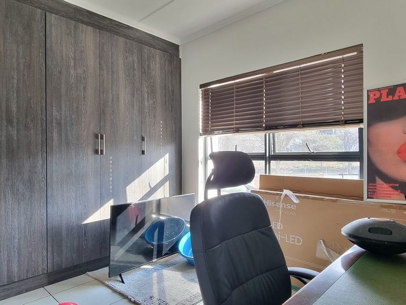 A bedroom featuring dark wood-grain built-in cupboards and venetian blinds, providing ample storage and natural light control.