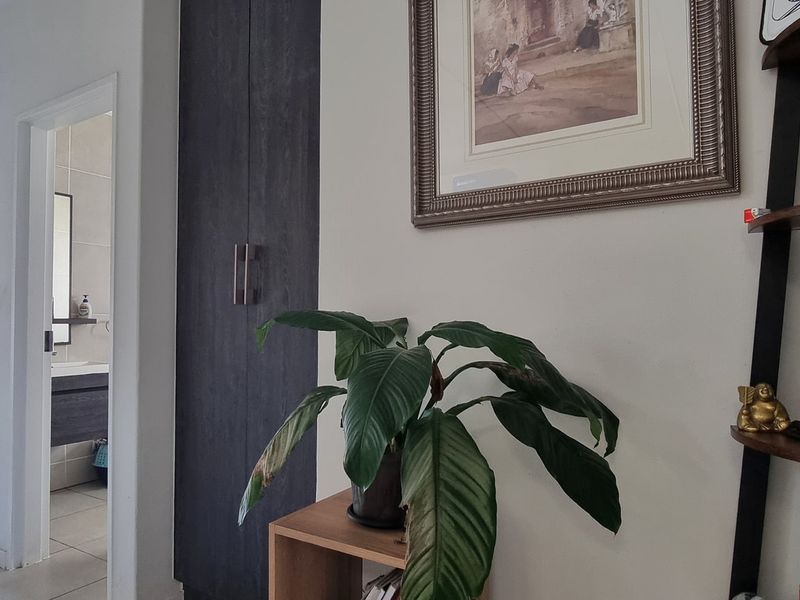 A functional hallway featuring a dark wood-finish built-in cupboard and tiled flooring, providing access to adjacent rooms.