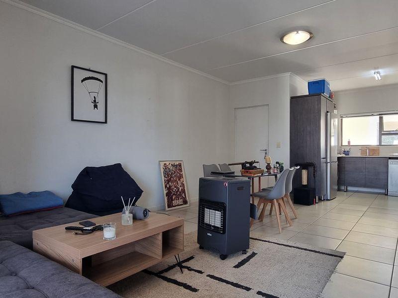 Open-plan living and kitchen area featuring tiled flooring, modern cabinetry, and functional layout suitable for comfortable apartment living.