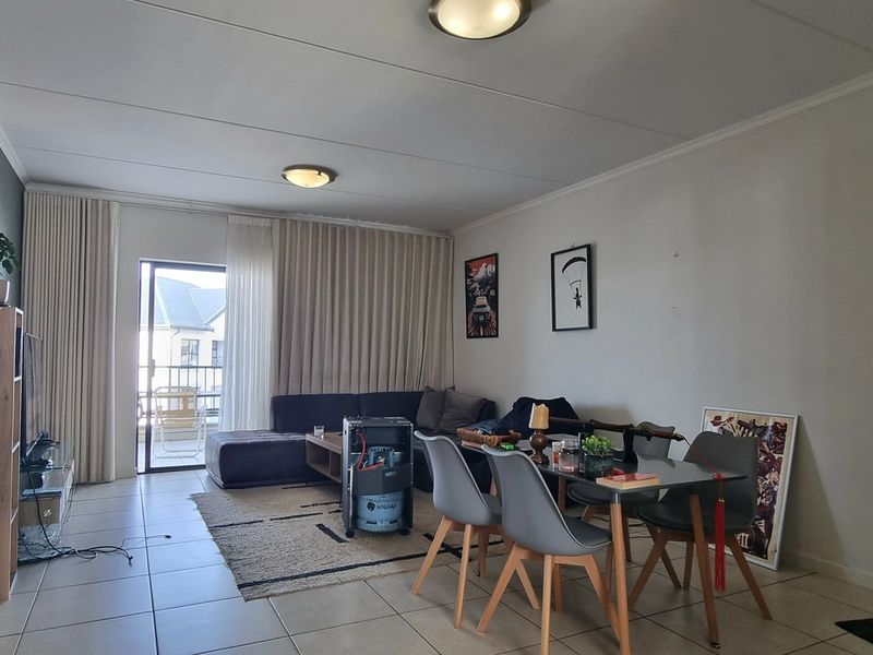 Open plan living and dining area featuring tiled flooring and a sliding glass door leading to an outdoor balcony.