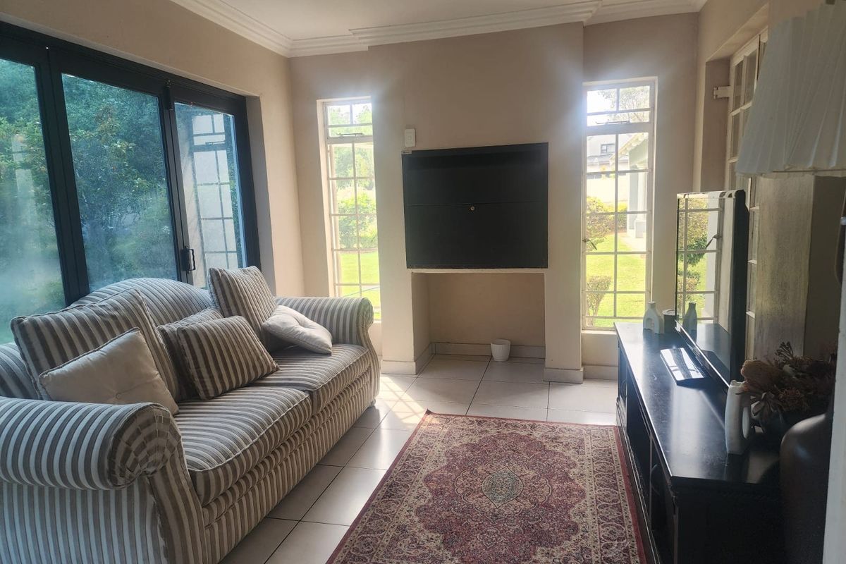 A sunlit living room featuring tiled flooring, a built-in fireplace, and large sliding glass doors providing access to the garden.