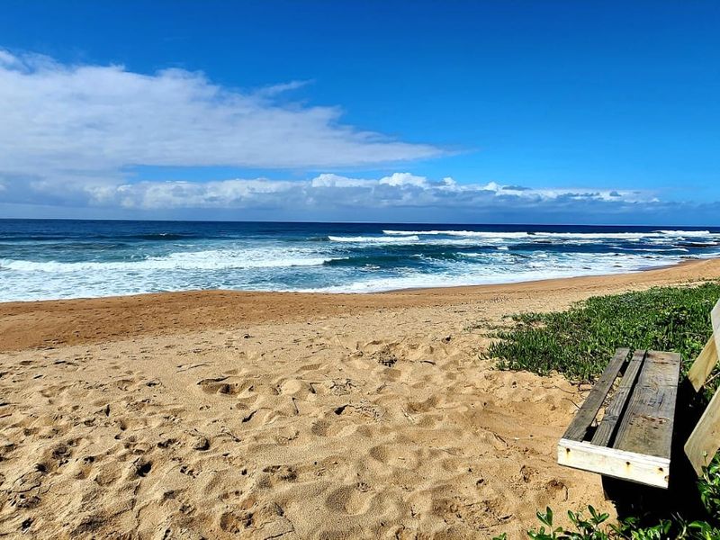 A scenic view of the sandy beach and ocean waves, highlighting the coastal location and natural surroundings of the property.