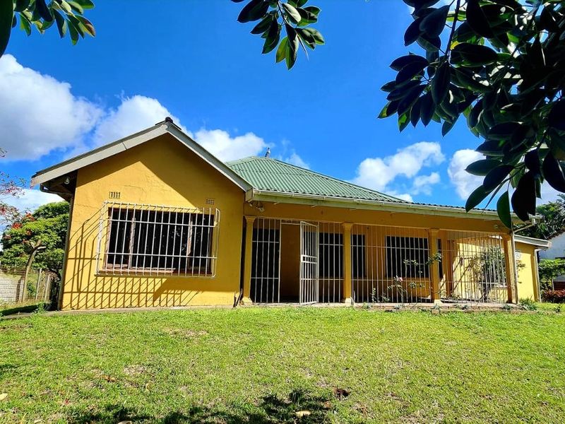 Front view of a single-story house featuring a covered veranda, metal security bars on windows, and a spacious front lawn.