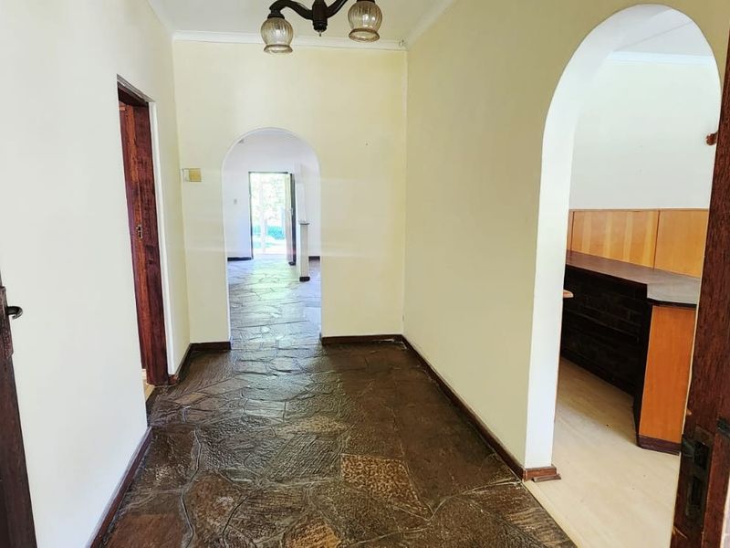 A spacious hallway featuring traditional stone flooring and arched architectural transitions leading to adjacent living areas.