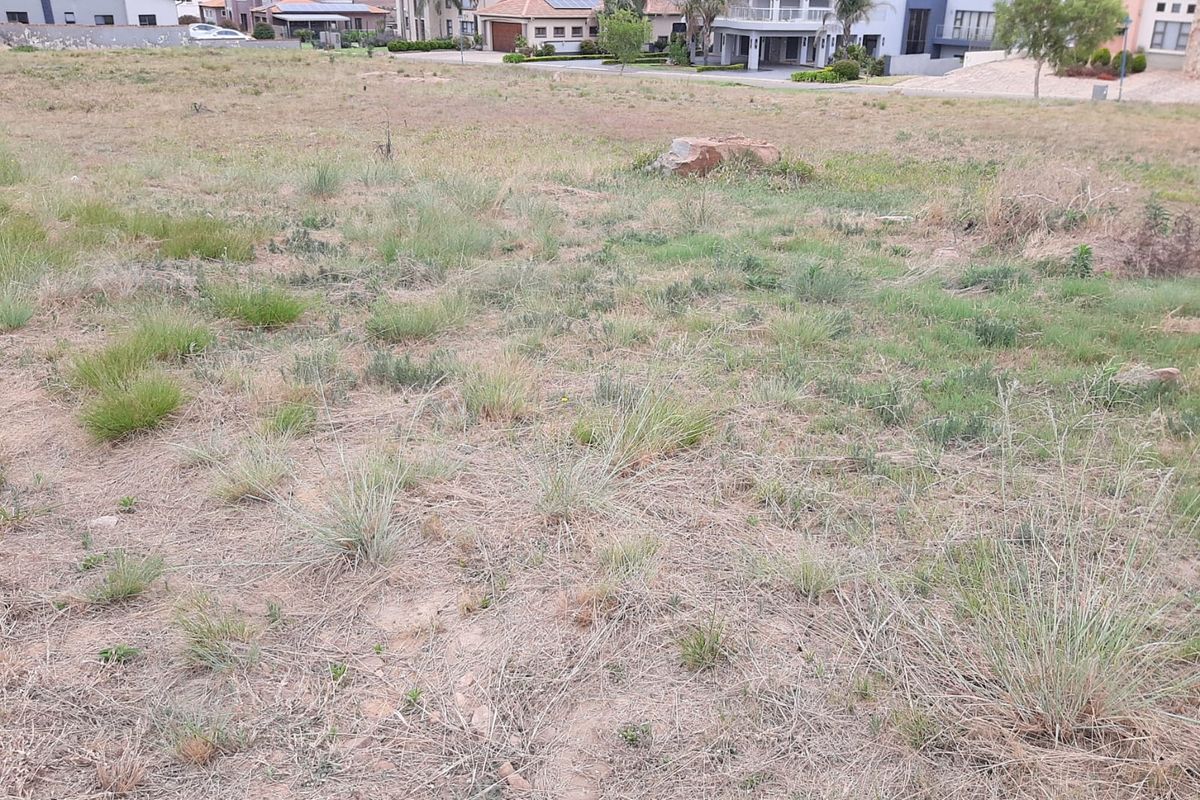 A view of a vacant residential plot of land with natural vegetation, situated in an established neighborhood.