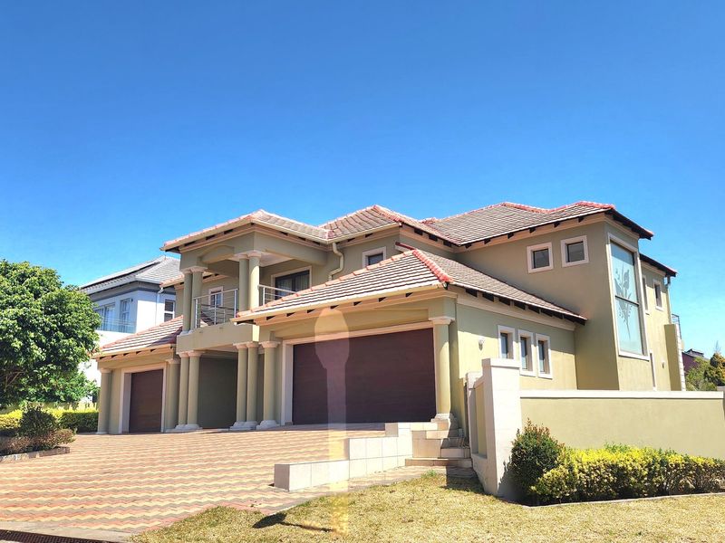 A well-maintained double-story residential property featuring a paved driveway, double garage, and a balcony with architectural columns under a tiled roof.