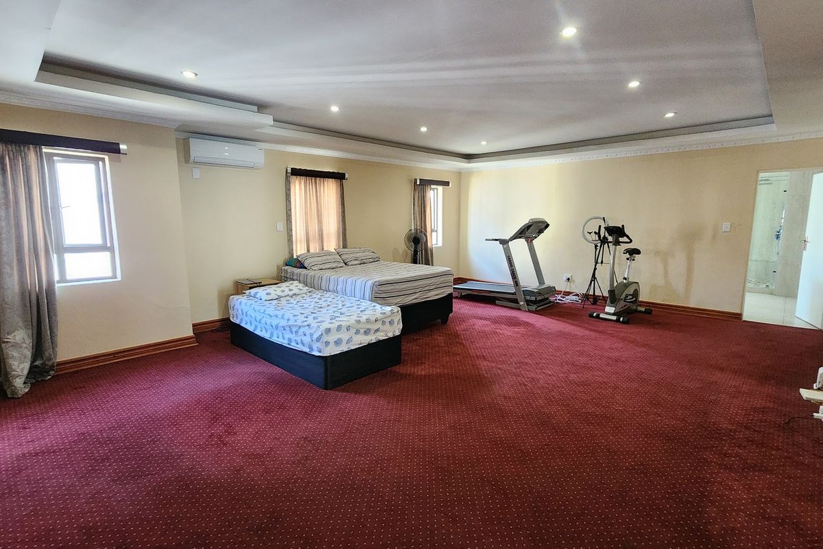Spacious bedroom featuring recessed ceiling lighting, cove molding, and a split-system air conditioner, offering ample room for various furniture arrangements.