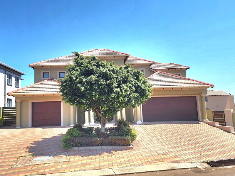 Front elevation of a double-story residential home featuring a paved driveway, double garage, and a well-maintained central garden bed.