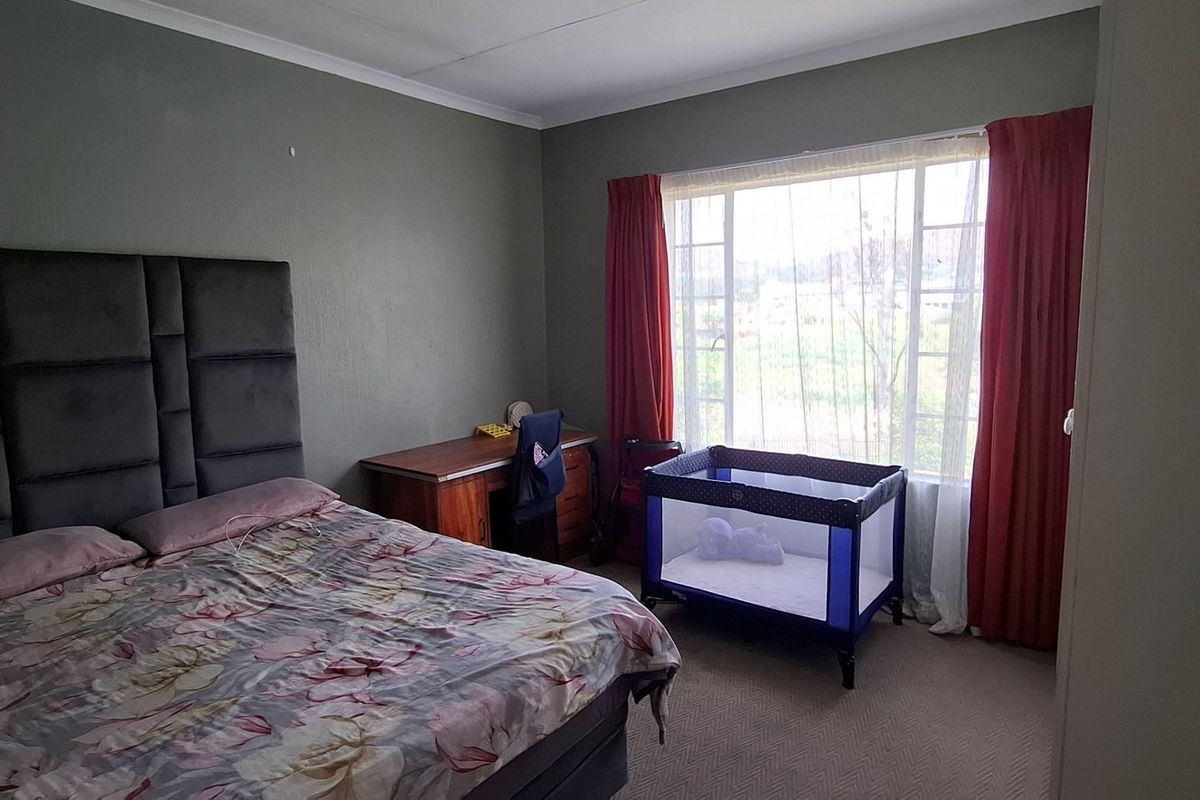 A bedroom featuring a large window with natural light and carpeted flooring.