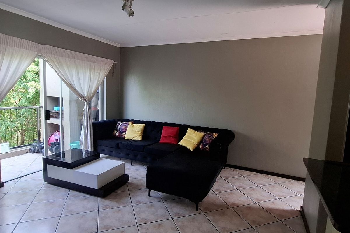 Spacious living area featuring tiled flooring and a large sliding glass door providing direct access to an outdoor balcony.