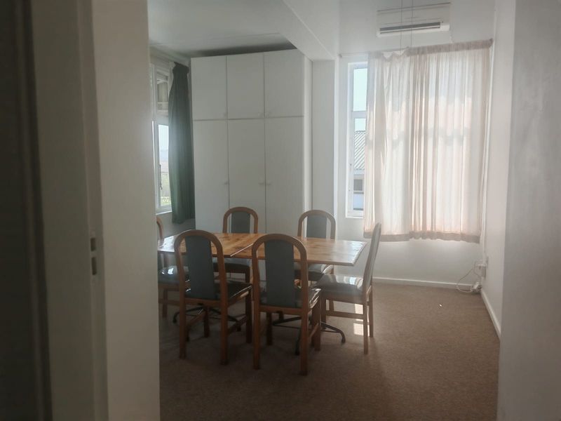 Dining room featuring built-in storage cupboards, carpeted flooring, and a wall-mounted air conditioning unit.