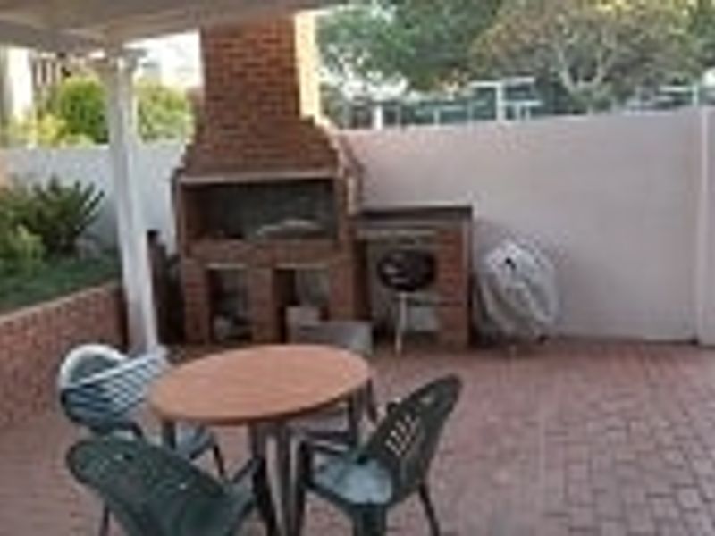 Covered outdoor patio area featuring a built-in brick braai and paved flooring, ideal for outdoor entertaining.