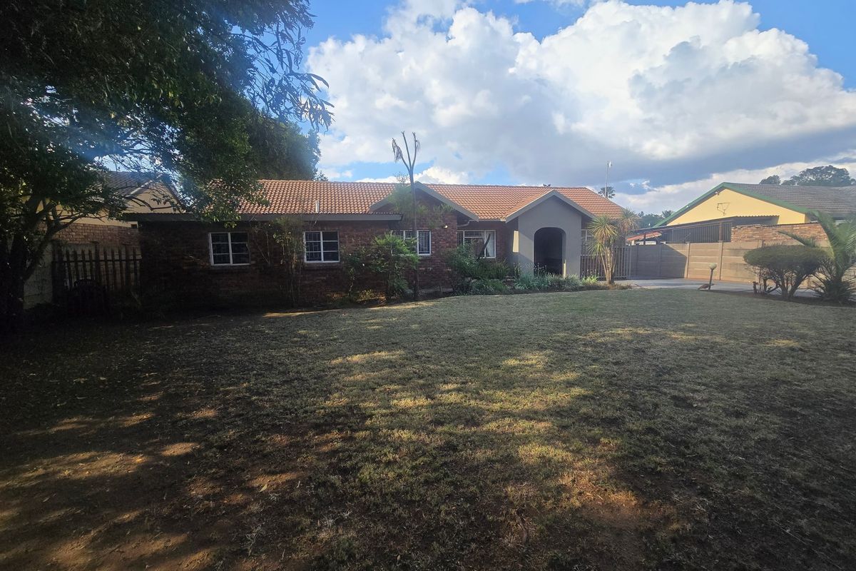 A view of the rear exterior of the house featuring a brick facade, tiled roof, and a spacious garden area.