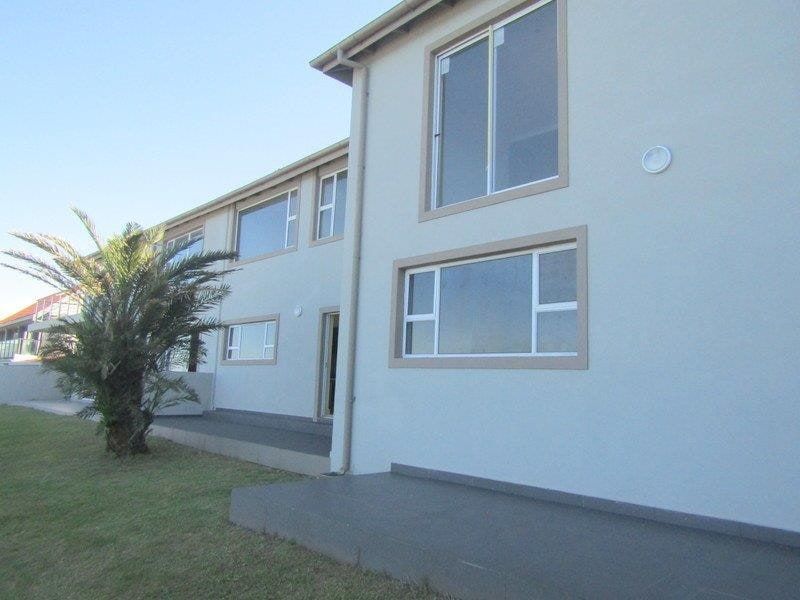 Rear elevation of the property featuring a paved patio area, low-maintenance exterior finish, and large aluminium-framed windows.