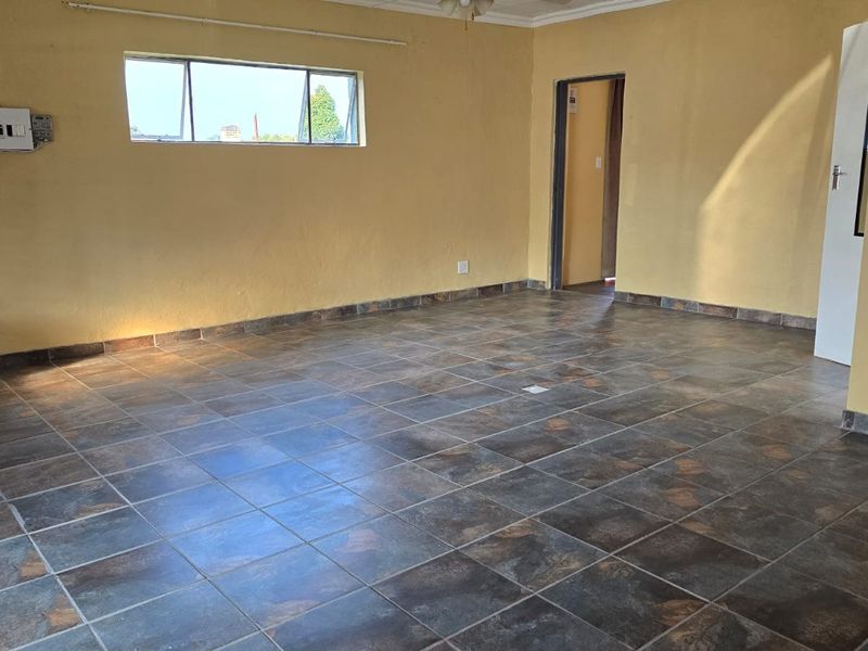 An empty living room featuring dark tiled flooring and yellow painted walls, providing a blank canvas for potential interior design updates.