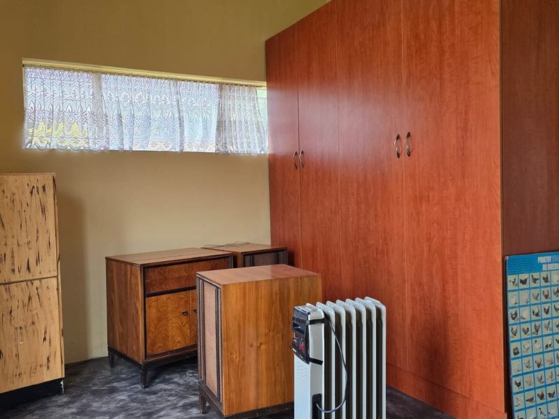 A bedroom featuring a large built-in wooden wardrobe and a horizontal window, providing functional storage and natural light.