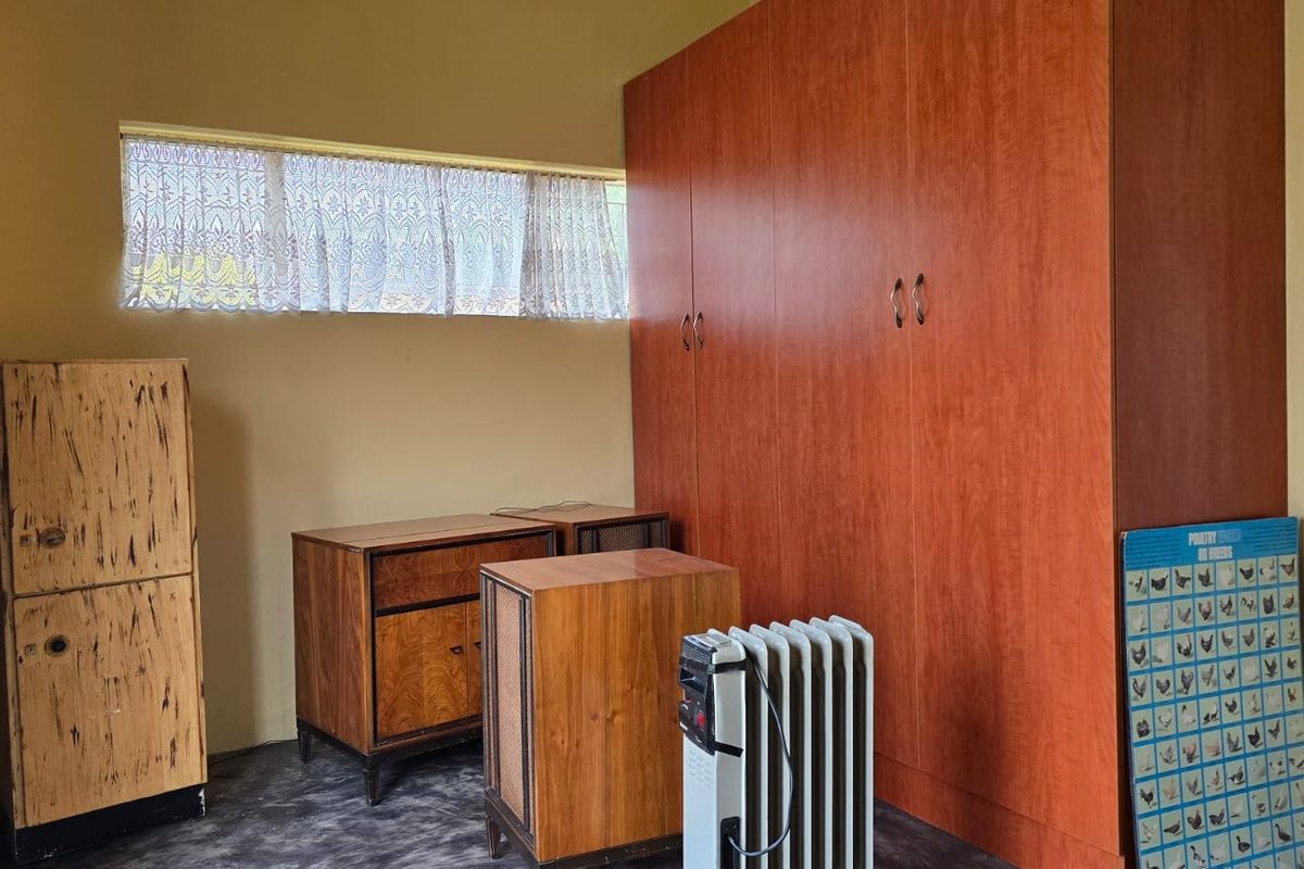 A bedroom featuring a large built-in wooden wardrobe and a horizontal window, providing functional storage and natural light.