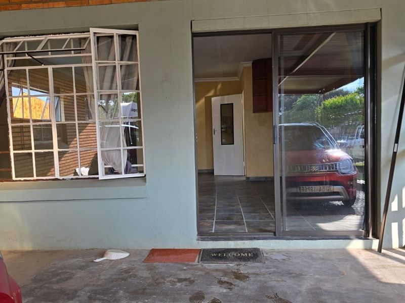 Covered patio area featuring tiled flooring, a sliding glass door entrance, and a security gate, providing access to the home's interior.